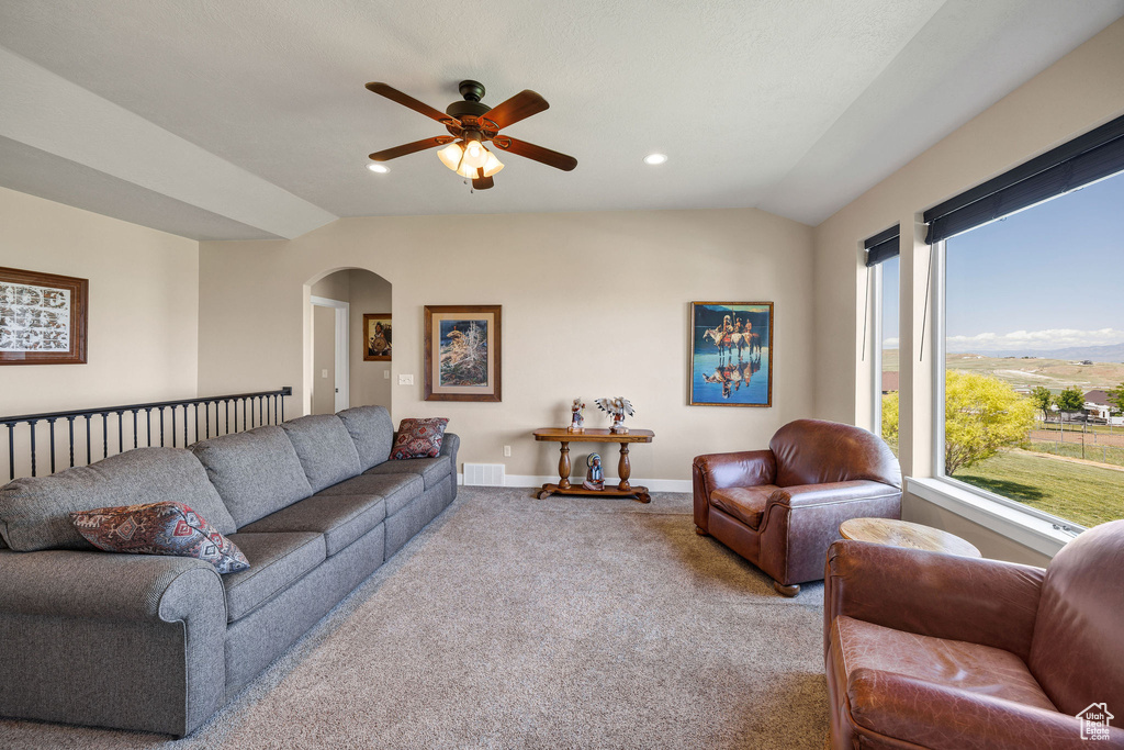 Living area with arched walkways, carpet, ceiling fan, lofted ceiling, and baseboards