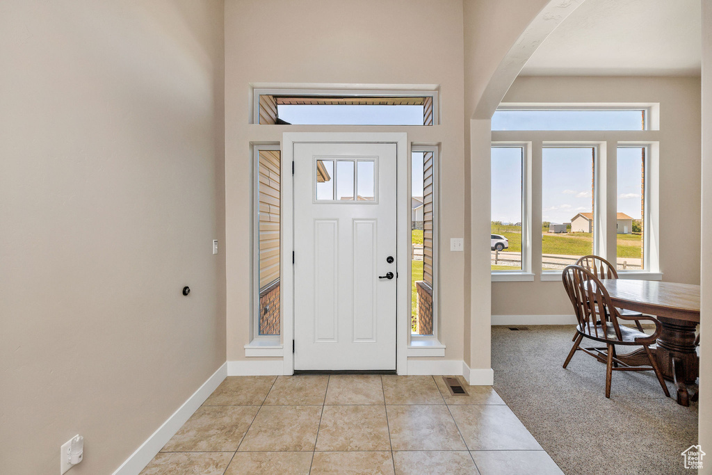 Foyer entrance featuring baseboards, light tile patterned floors, and arched walkways
