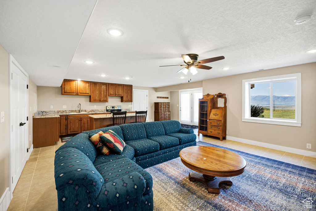 Living area with light tile patterned floors, baseboards, recessed lighting, and a ceiling fan