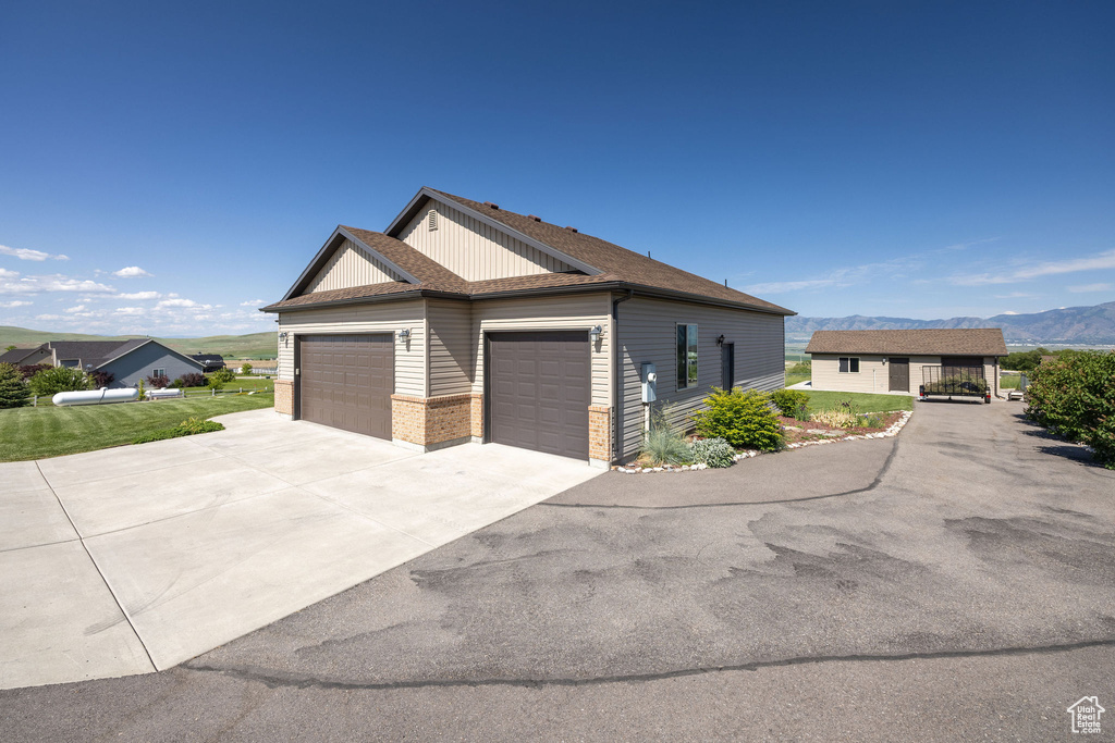 View of home\\\\\\\'s exterior with an attached garage, driveway, a mountain view, a shingled roof, and brick siding