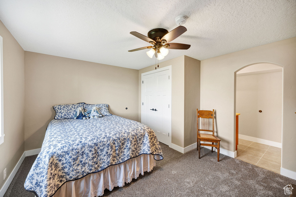 Bedroom with carpet flooring, ceiling fan, baseboards, and a textured ceiling