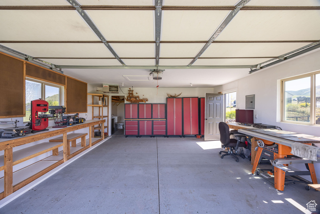 Garage with a workshop area, a garage door opener, and electric panel