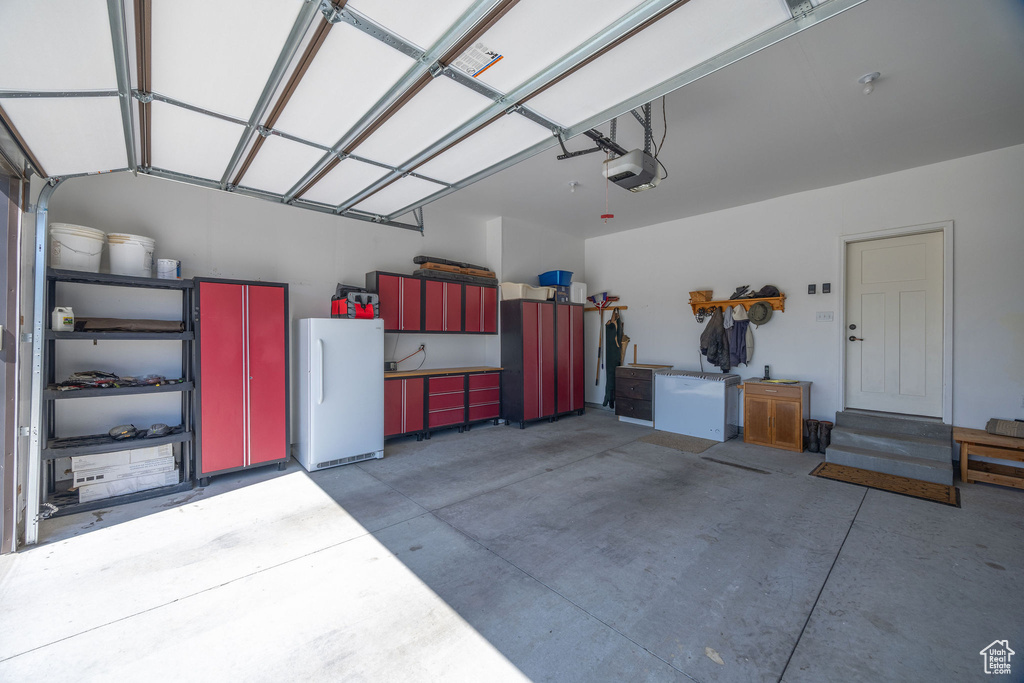 Garage featuring freestanding refrigerator and a garage door opener