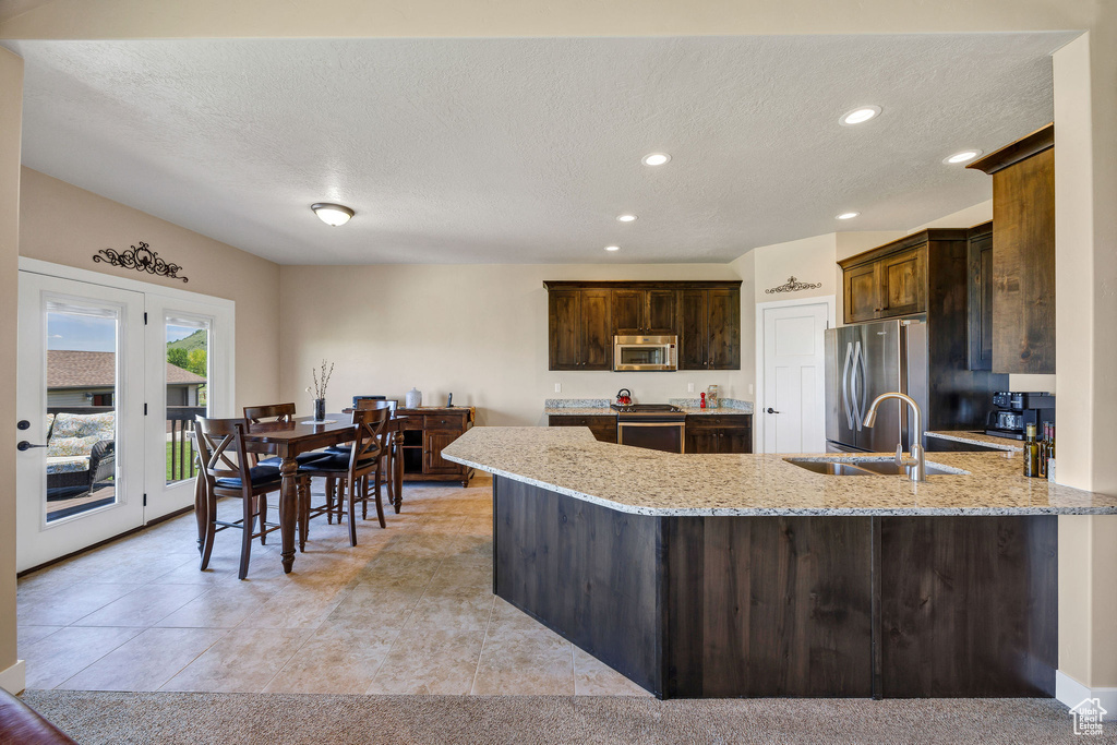 Kitchen featuring stainless steel appliances, a sink, light stone counters, recessed lighting, and a textured ceiling
