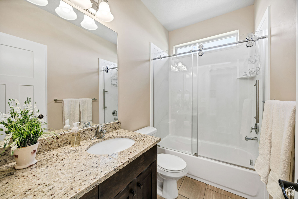 Full bathroom with vanity, toilet, and shower / bath combination with glass door