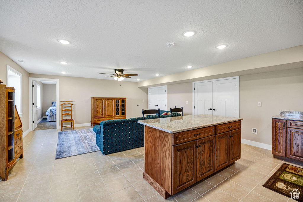 Kitchen featuring ceiling fan, recessed lighting, light tile patterned floors, a textured ceiling, and a center island
