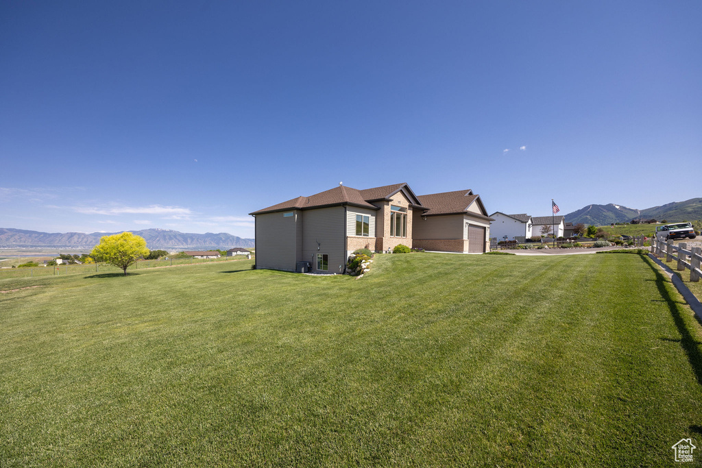 View of grassy yard with a mountain view and a garage