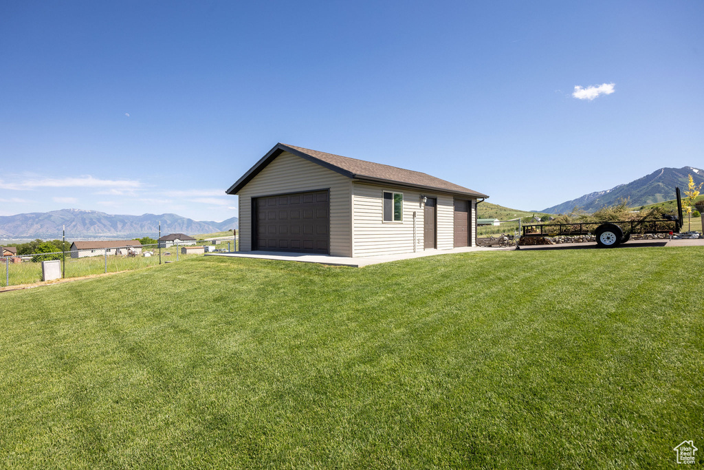 Exterior space with a detached garage, a mountain view, and an outbuilding