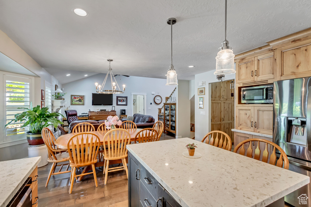 Kitchen with appliances with stainless steel finishes, light wood finished floors, open floor plan, a center island, and a chandelier