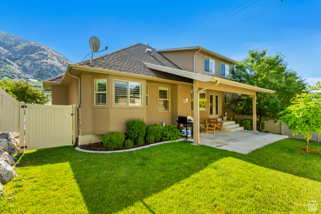 Rear view of property with stucco siding, a patio area, roof with shingles, and a mountain view