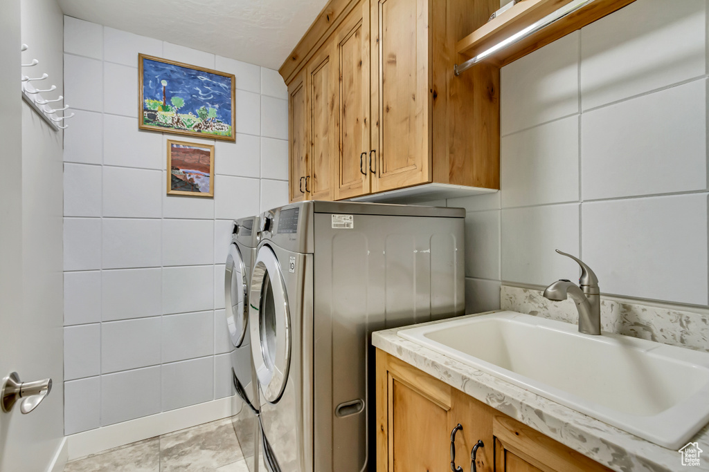 Laundry room featuring cabinet space, tile walls, and independent washer and dryer