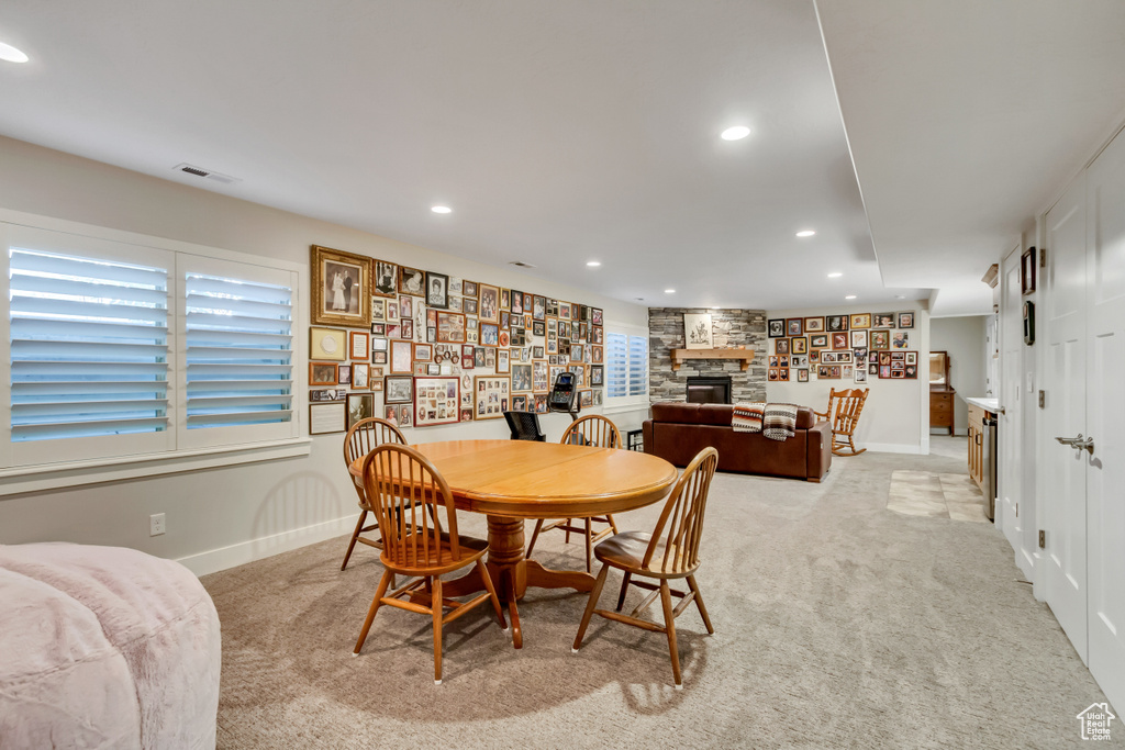 Dining area featuring light carpet, a stone fireplace, recessed lighting, and baseboards