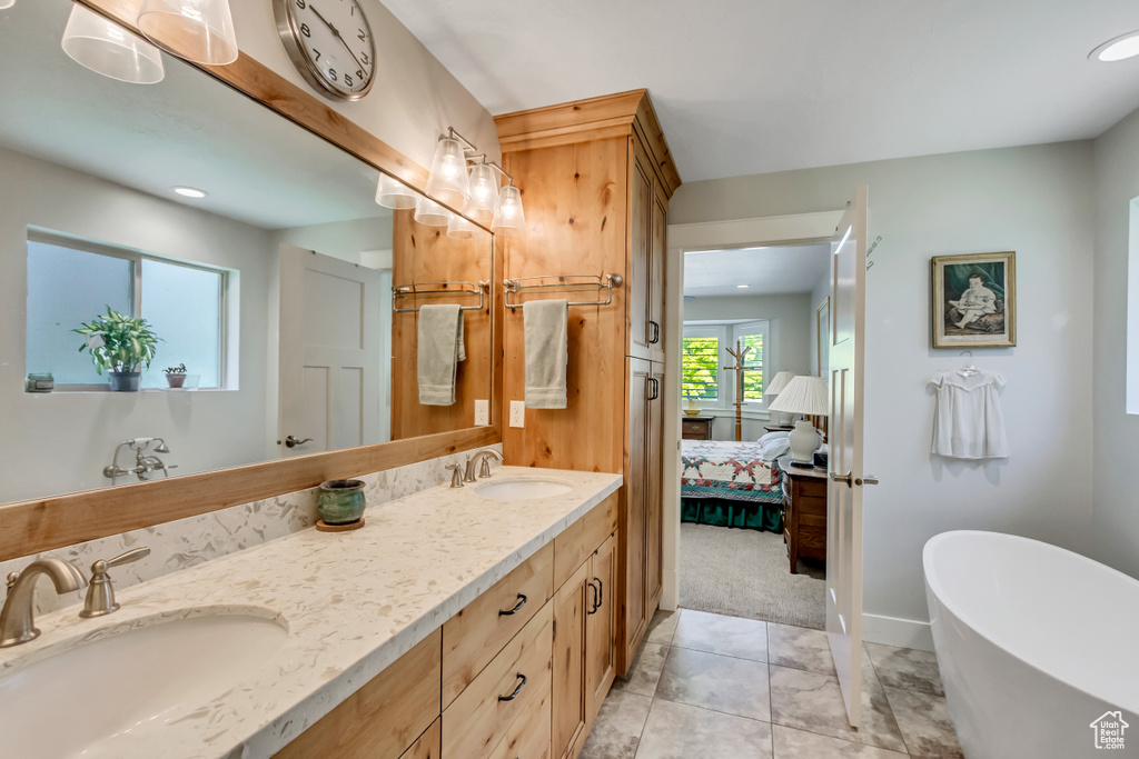 Ensuite bathroom with double vanity, a freestanding bath, recessed lighting, and baseboards