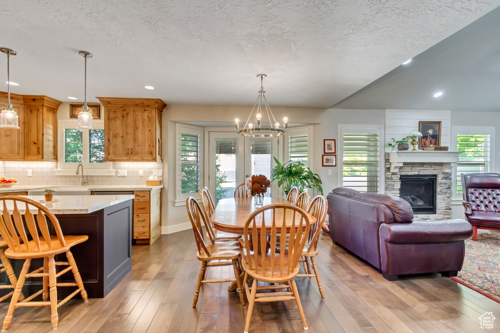 Dining area with a chandelier, light wood-style flooring, a fireplace, recessed lighting, and a textured ceiling