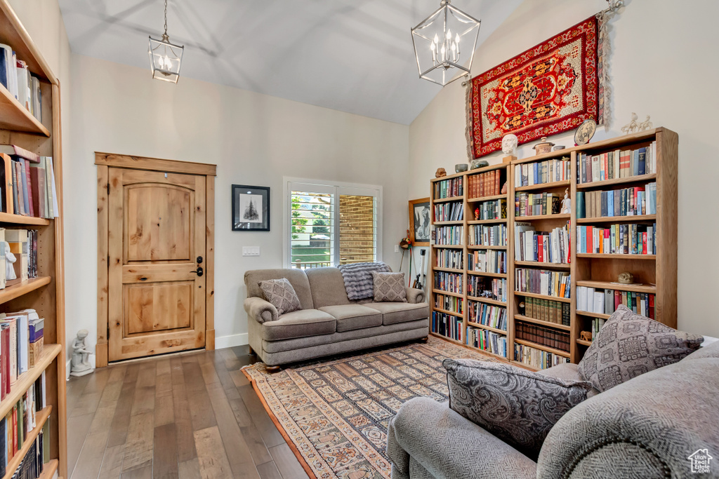 Sitting room featuring high vaulted ceiling, wood-type flooring, a chandelier, and wall of books
