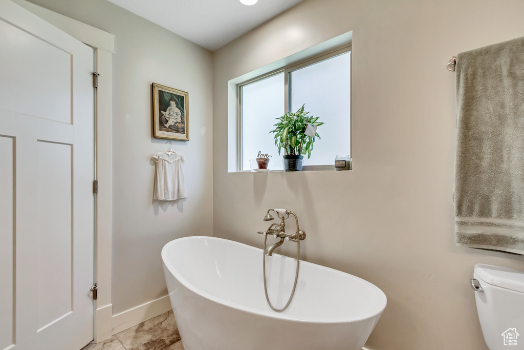 Bathroom with a freestanding bath, baseboards, and toilet