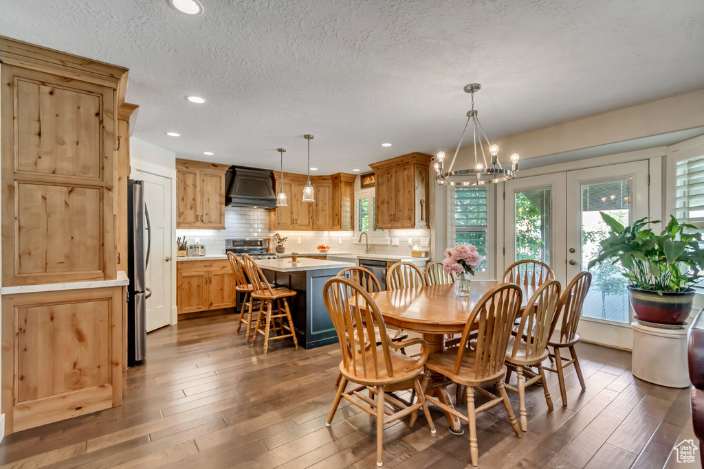 Dining room featuring hardwood / wood-style flooring, a chandelier, a textured ceiling, and recessed lighting
