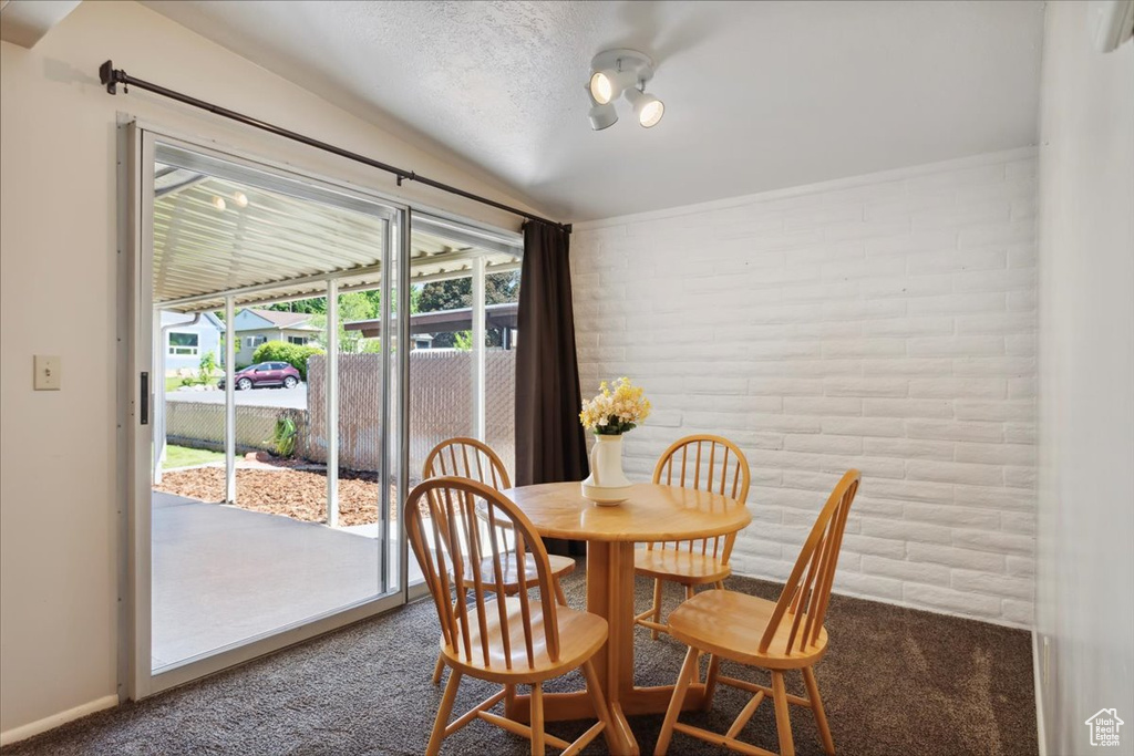 Carpeted dining space with lofted ceiling