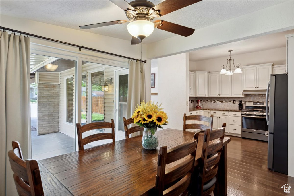Dining area with ceiling fan, a chandelier, and dark wood-type flooring
