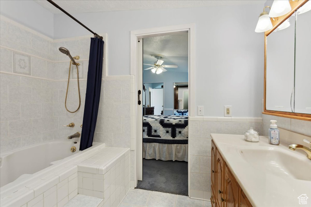 Full bath featuring ensuite bath, tile patterned floors, shower / tub combo with curtain, a ceiling fan, and tile walls