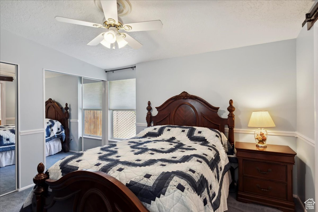 Carpeted bedroom with a textured ceiling and ceiling fan