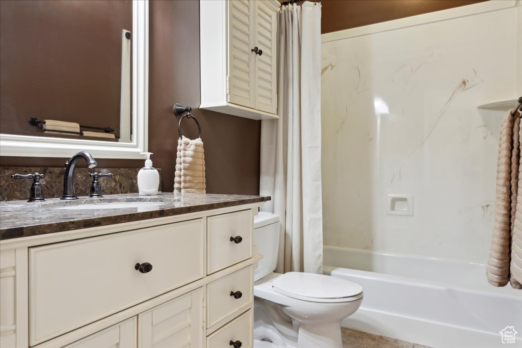 Bathroom featuring toilet, vanity, and shower / bath combination with curtain