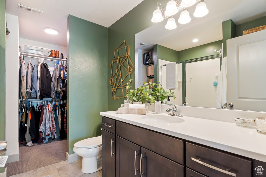Bathroom with vanity, a shower stall, a spacious closet, toilet, and tile patterned flooring