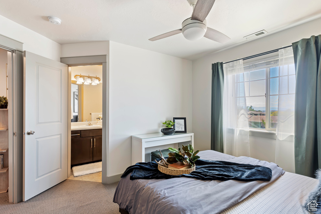 Bedroom featuring light colored carpet, a sink, ensuite bath, and ceiling fan