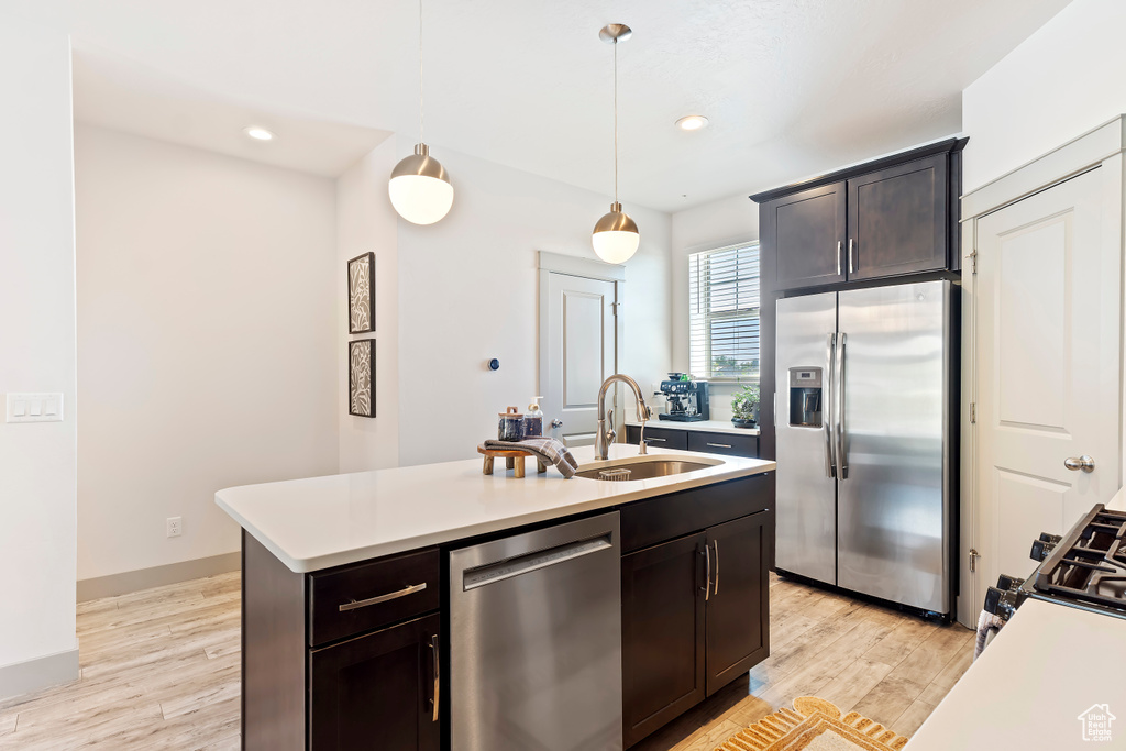 Kitchen featuring stainless steel appliances, a sink, light countertops, pendant lighting, and recessed lighting