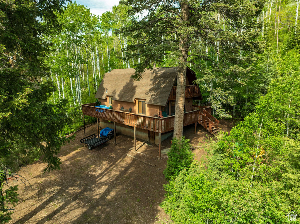 Back of house featuring a deck, a shingled roof, and stairs