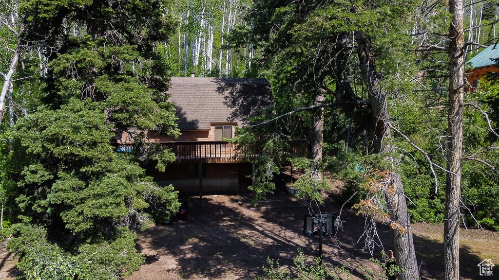 Back of house with a deck and a shingled roof