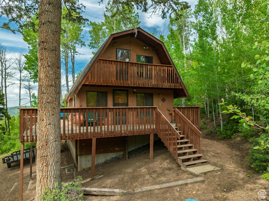 Rear view of property featuring a gambrel roof and a wooden deck