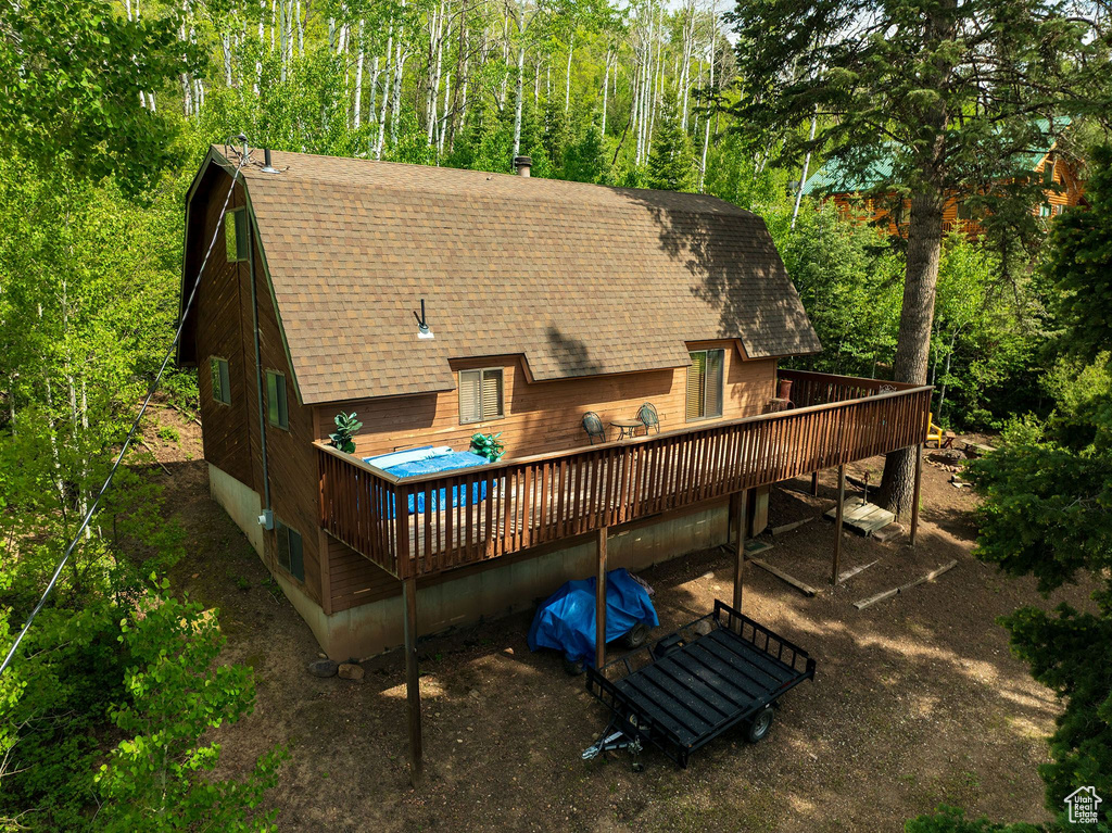Back of property with a shingled roof and a deck