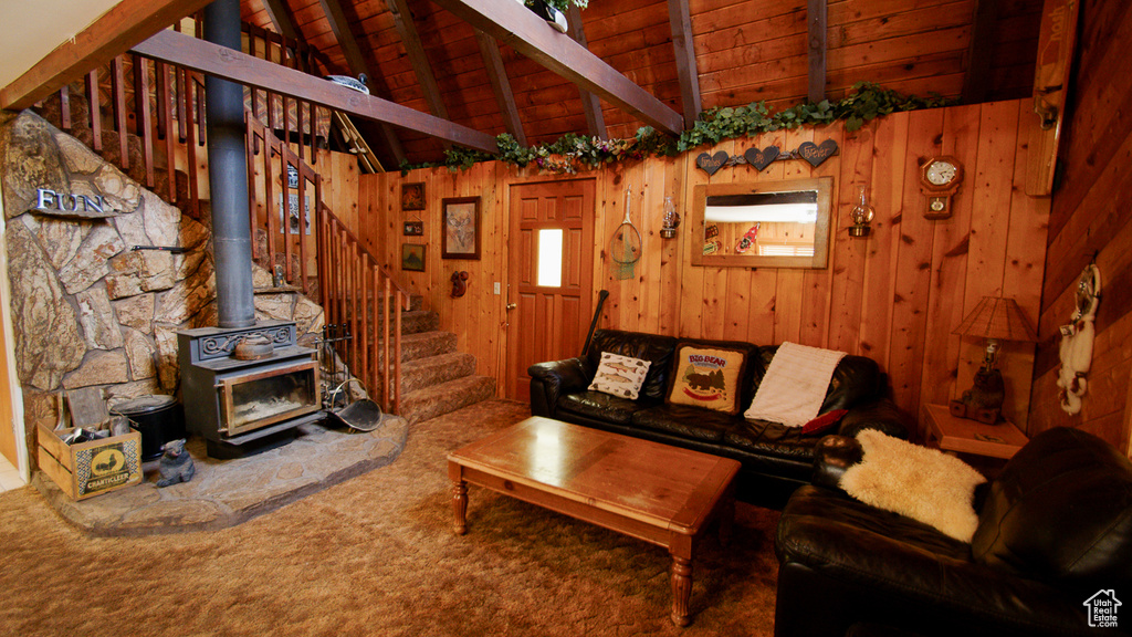 Living area with stairway, wood walls, wooden ceiling, carpet, and a wood stove