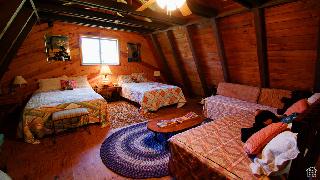 Bedroom featuring wood walls, wood finished floors, and lofted ceiling