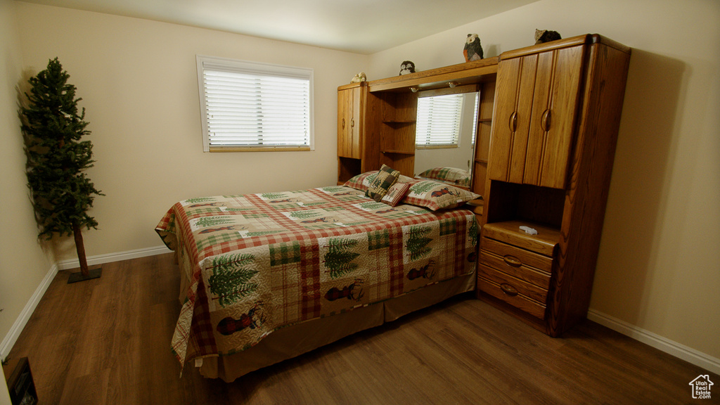Bedroom with dark wood-style flooring, multiple windows, and baseboards