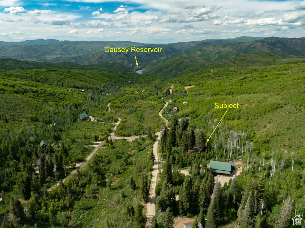 Aerial view of property and surrounding area with mountains and a heavily wooded area
