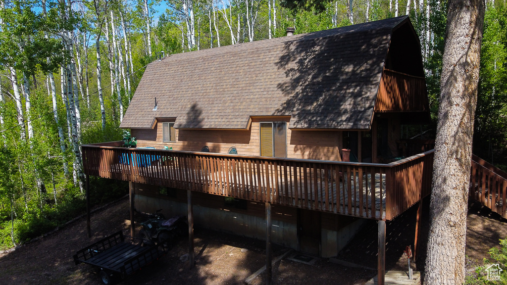 Back of property with a shingled roof and a deck