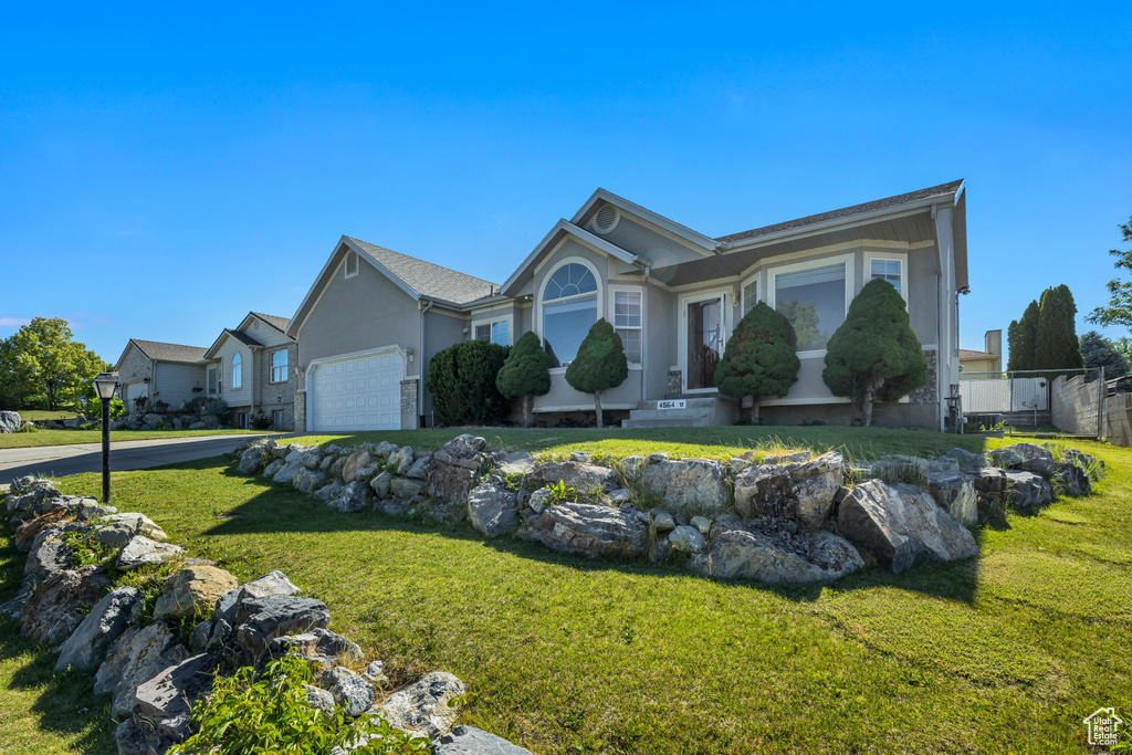 Ranch-style house with stucco siding, a front lawn, an attached garage, and driveway