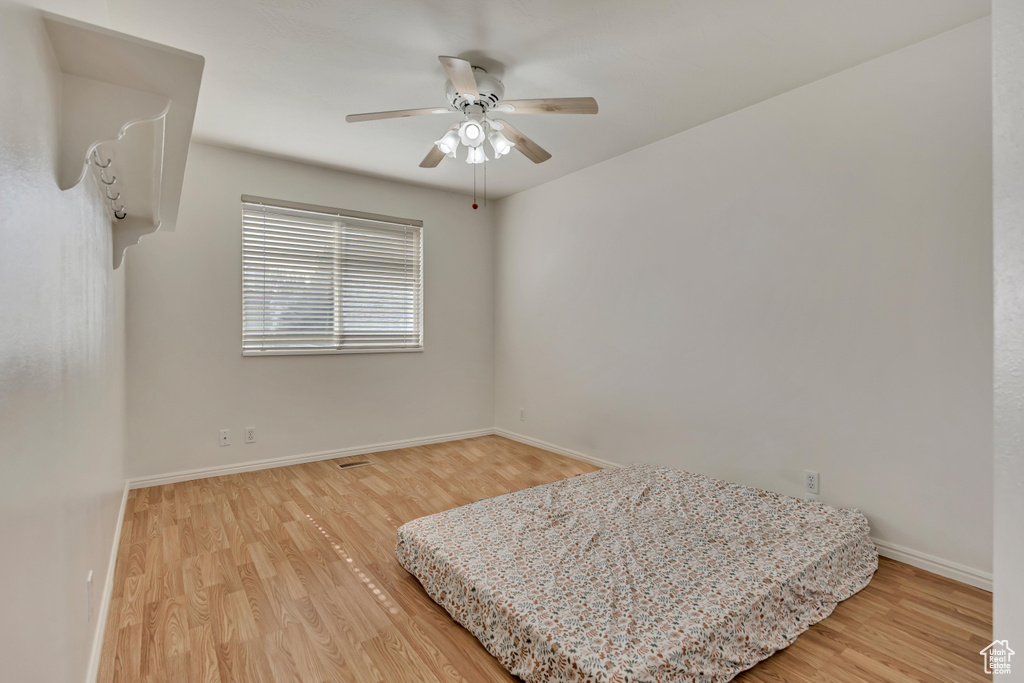 Bedroom with light wood finished floors, baseboards, and a ceiling fan