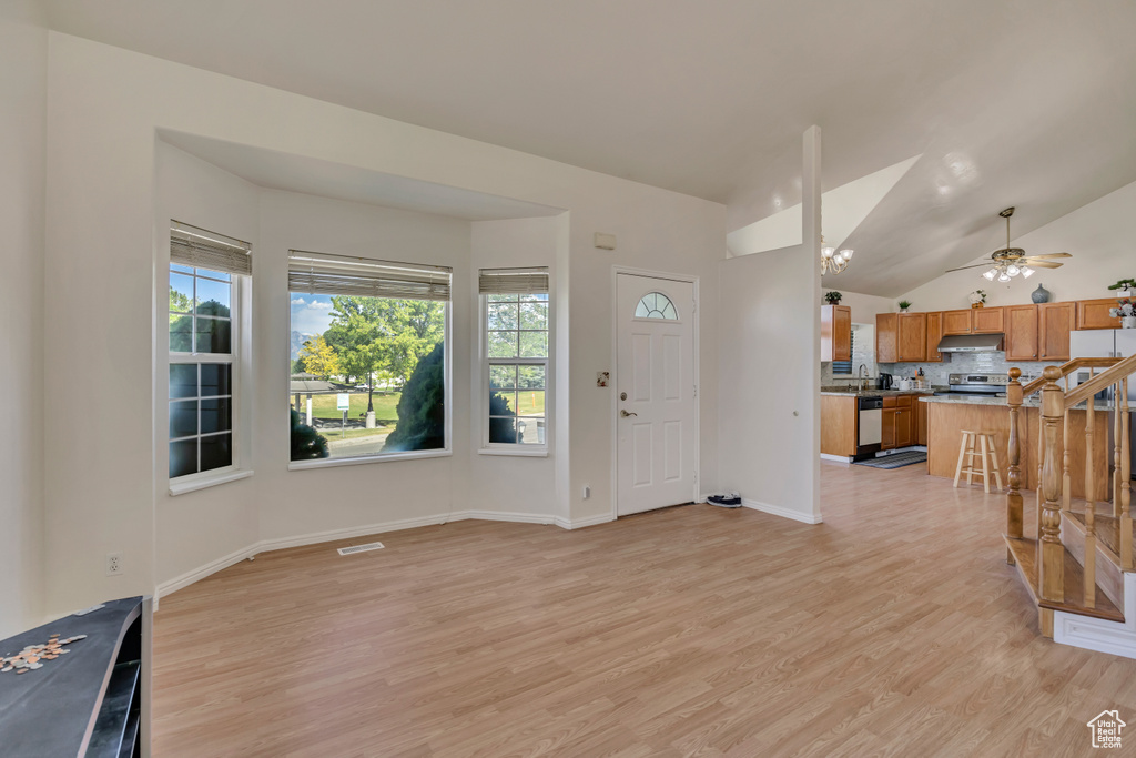 Entrance foyer featuring light wood finished floors, lofted ceiling, ceiling fan, and baseboards