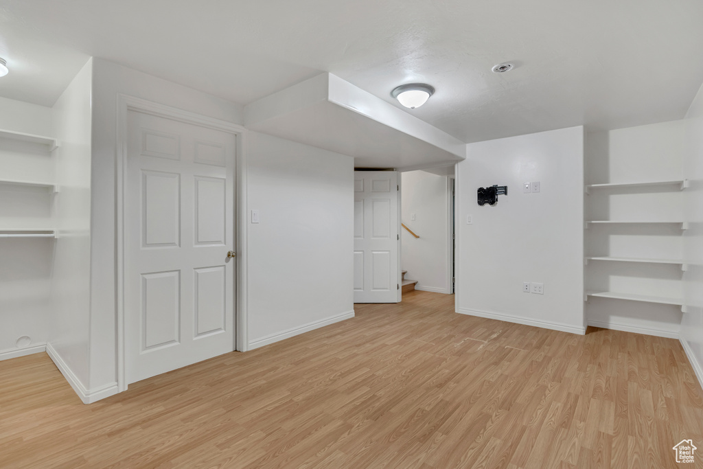 Finished basement with light wood-style floors, baseboards, and stairway