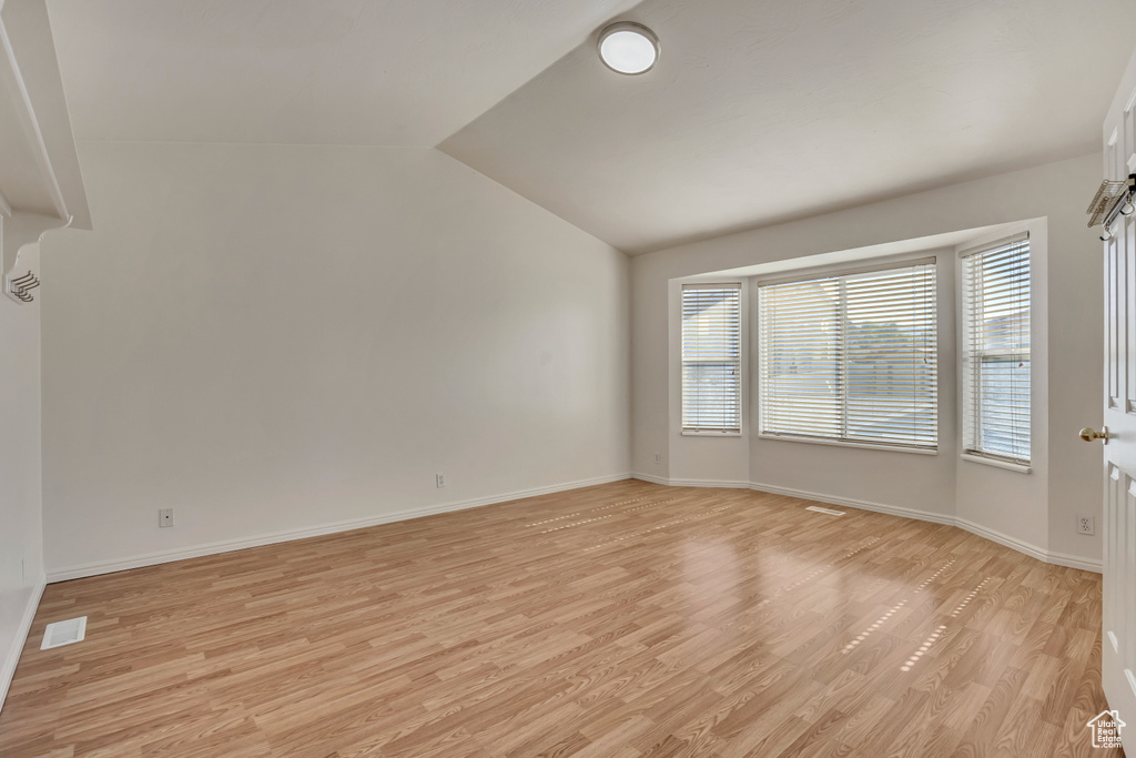 Spare room with light wood-style floors, lofted ceiling, and baseboards