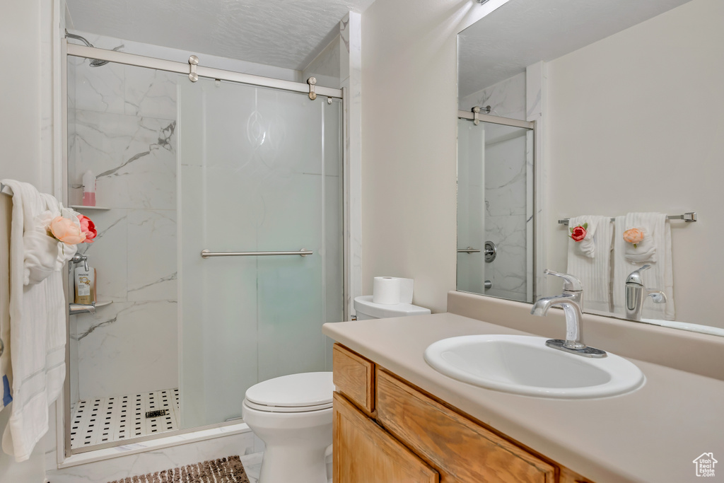 Full bathroom with a marble finish shower, toilet, and vanity
