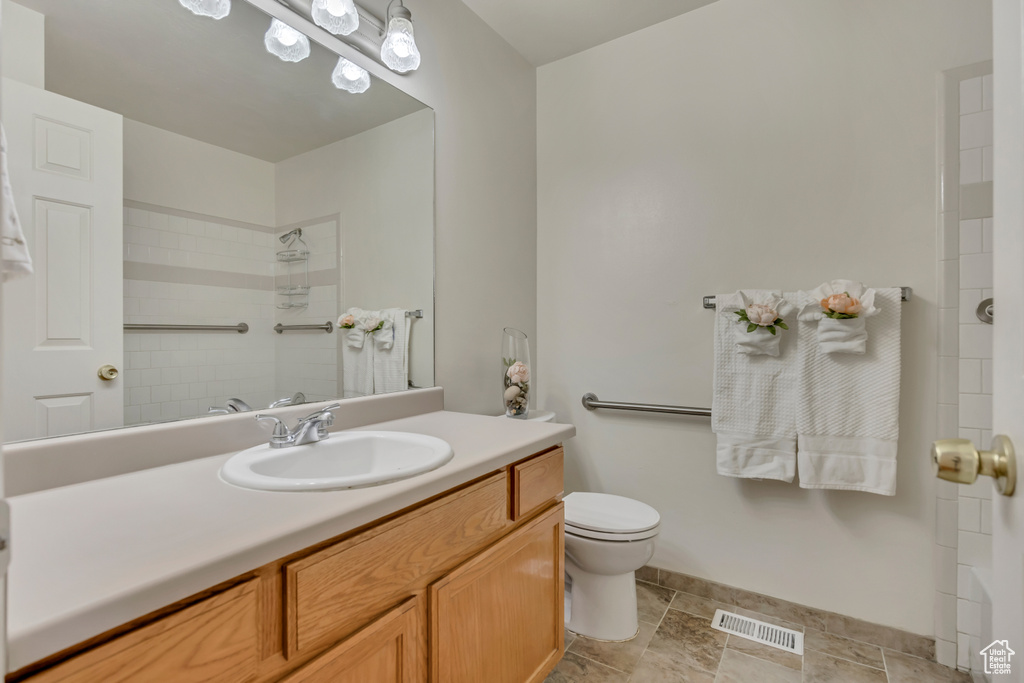 Bathroom with toilet, vanity, a shower, and baseboards