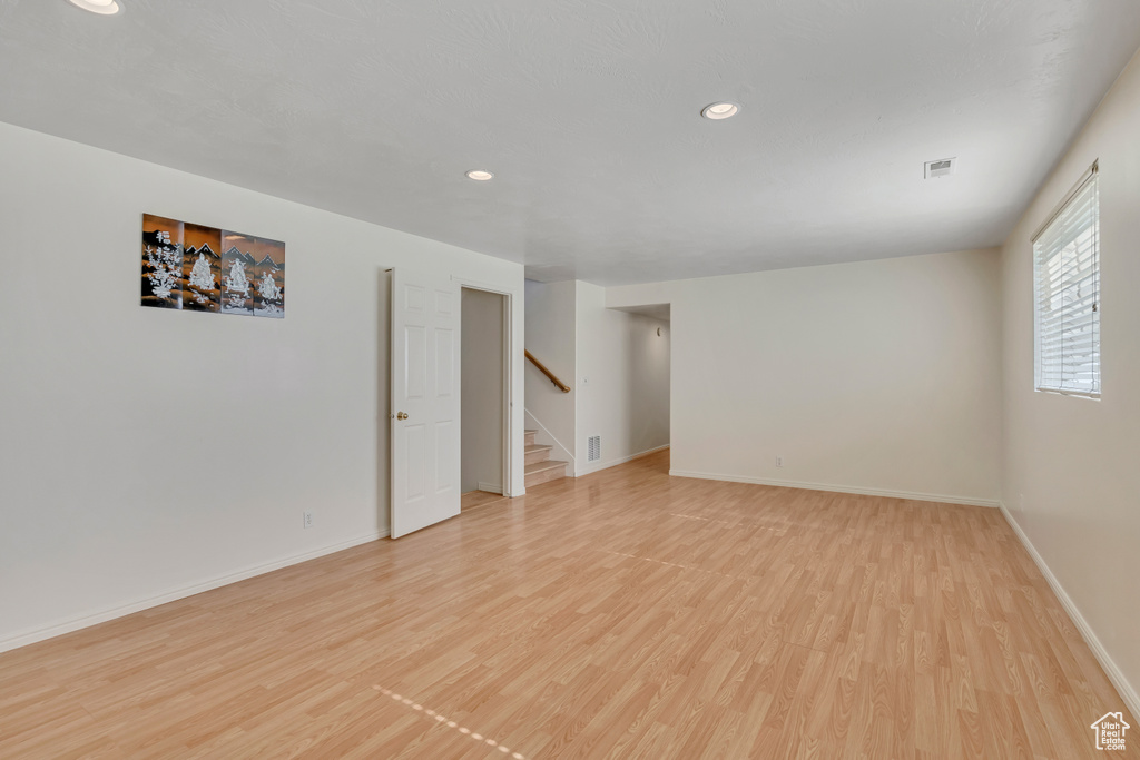 Unfurnished room with light wood finished floors, baseboards, recessed lighting, and stairway
