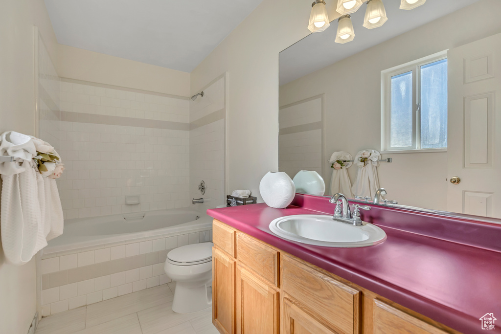 Full bath with tile patterned flooring, toilet, vanity, and tiled shower / bath combo