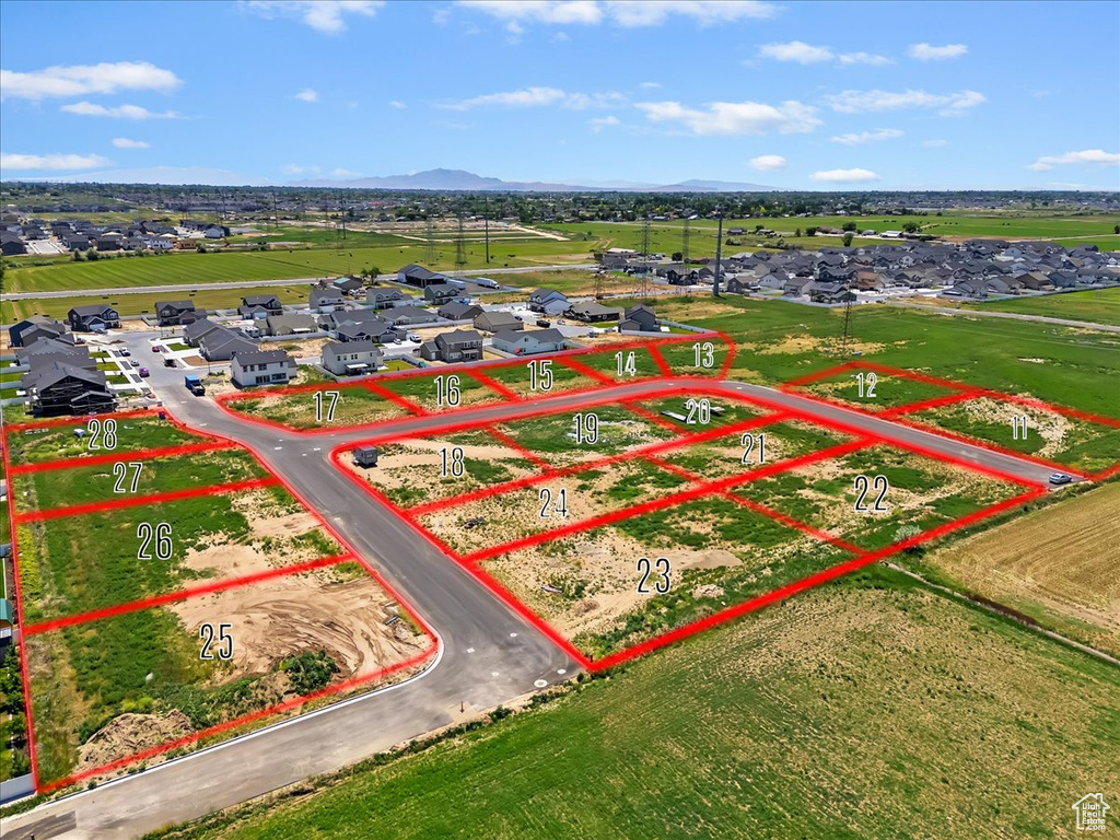 Aerial view of residential area with property boundaries highlighted and a mountainous background