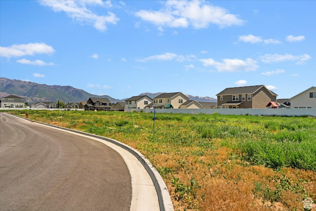 View of asphalt road featuring a residential view, curbs, and a mountain view