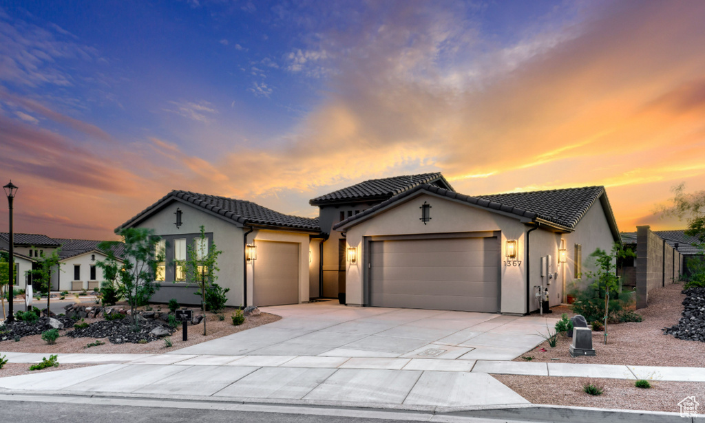 Mediterranean / spanish-style home with a garage, stucco siding, concrete driveway, and a tiled roof